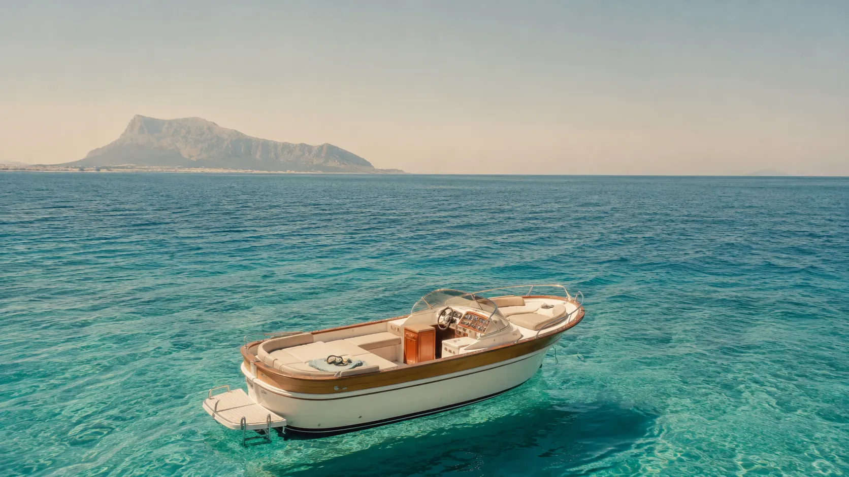 Una barca alla deriva su un mare turchese al largo della costa di Palermo, con Monte Pellegrino sullo sfondo